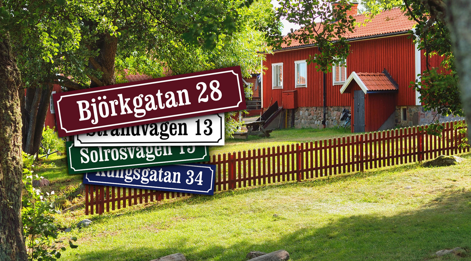 Klassiska husskyltar med gatunamn framför röd svensk villa i lantlig miljö